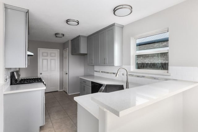 kitchen with gray cabinets, black dishwasher, sink, kitchen peninsula, and stainless steel gas range