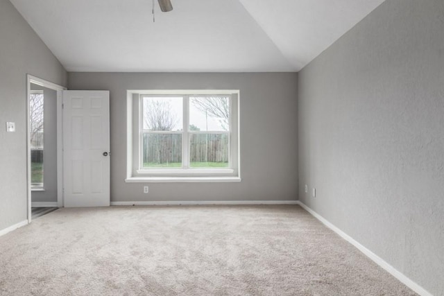 carpeted spare room featuring lofted ceiling and ceiling fan