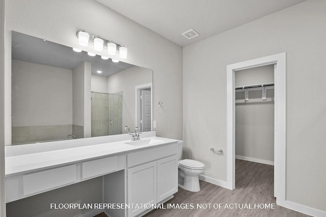 bathroom with wood-type flooring, vanity, toilet, and a shower with door