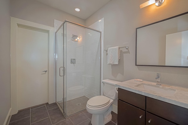 bathroom with tile patterned floors, vanity, a shower with shower door, and toilet