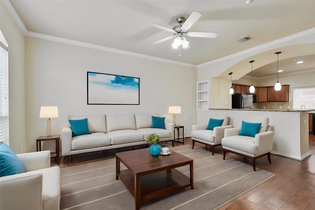 living room with ceiling fan, sink, dark wood-type flooring, and ornamental molding