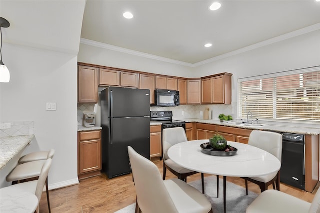 kitchen featuring tasteful backsplash, sink, black appliances, pendant lighting, and light hardwood / wood-style flooring