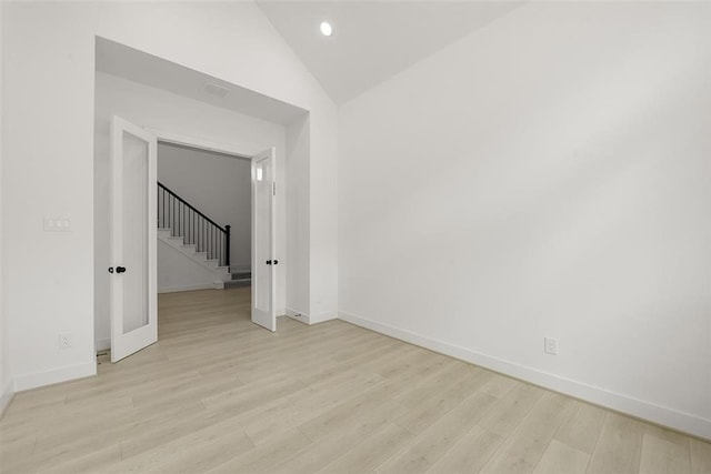 unfurnished room with light wood-type flooring and vaulted ceiling