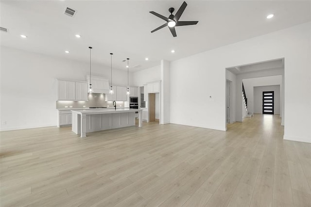 unfurnished living room featuring ceiling fan, sink, and light hardwood / wood-style floors