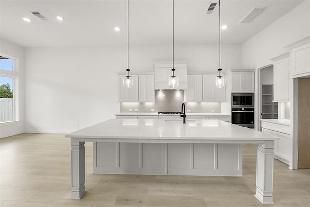 kitchen featuring black oven, a spacious island, and decorative light fixtures