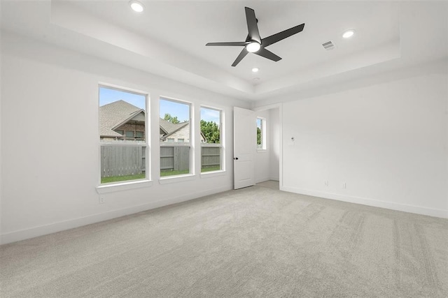 carpeted spare room featuring ceiling fan and a raised ceiling