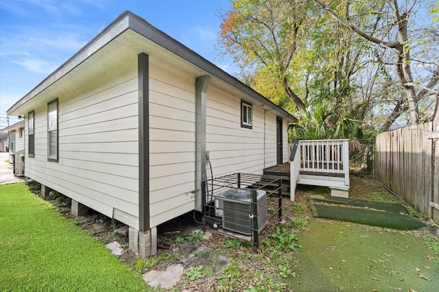 view of side of property with a yard, central AC, and a wooden deck