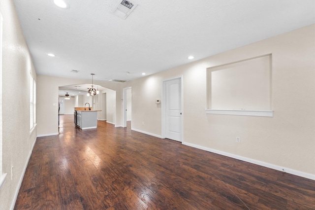 unfurnished living room featuring dark hardwood / wood-style floors, ceiling fan, and sink