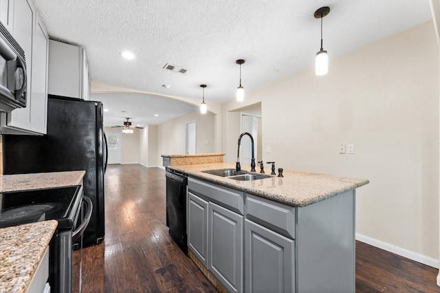 kitchen with a kitchen island with sink, black appliances, sink, ceiling fan, and a textured ceiling