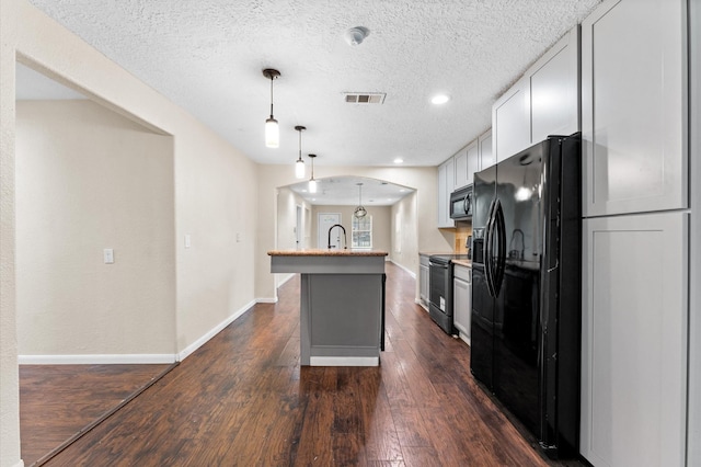 kitchen featuring pendant lighting, a kitchen island with sink, black appliances, sink, and white cabinetry