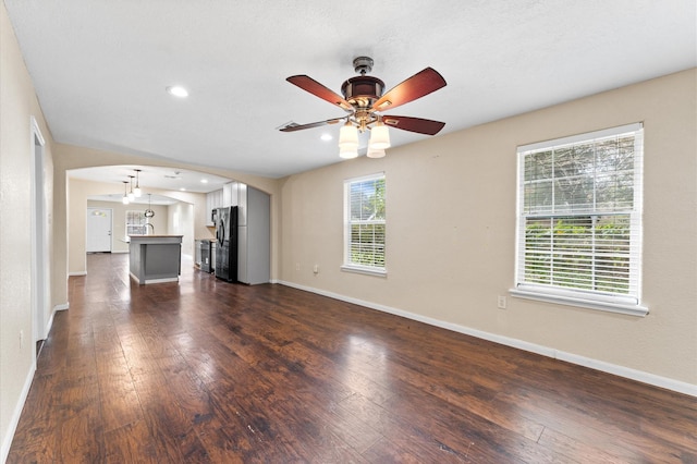 unfurnished living room featuring ceiling fan, plenty of natural light, and dark hardwood / wood-style floors