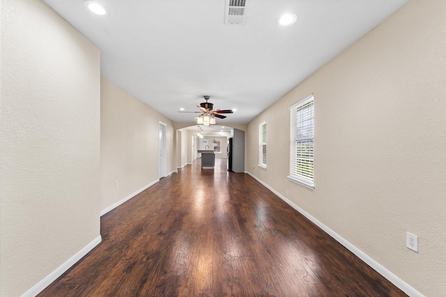 unfurnished living room featuring ceiling fan and dark wood-type flooring