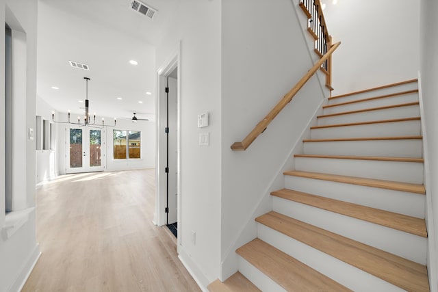 staircase featuring ceiling fan with notable chandelier and wood-type flooring