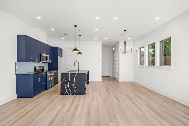 kitchen featuring light hardwood / wood-style flooring, blue cabinetry, an island with sink, decorative light fixtures, and stainless steel appliances