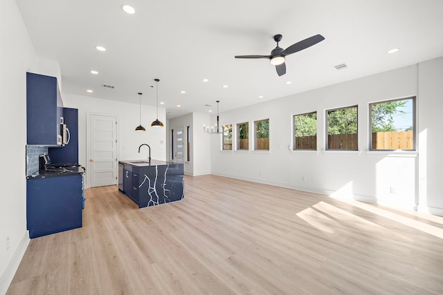 kitchen featuring blue cabinetry, sink, light hardwood / wood-style floors, a center island with sink, and ceiling fan with notable chandelier