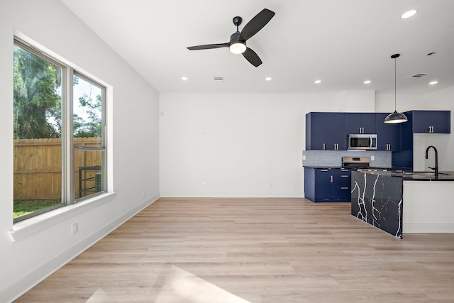 kitchen with ceiling fan, tasteful backsplash, light hardwood / wood-style flooring, blue cabinets, and appliances with stainless steel finishes