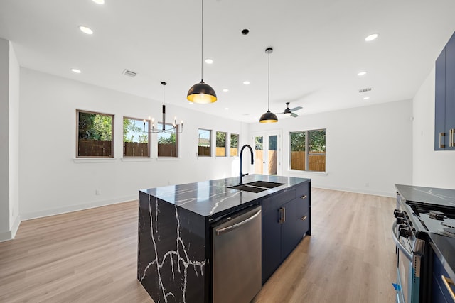 kitchen with sink, stainless steel appliances, an island with sink, ceiling fan with notable chandelier, and light wood-type flooring