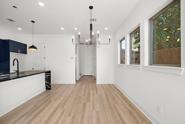 kitchen featuring sink, blue cabinetry, wood-type flooring, a notable chandelier, and hanging light fixtures