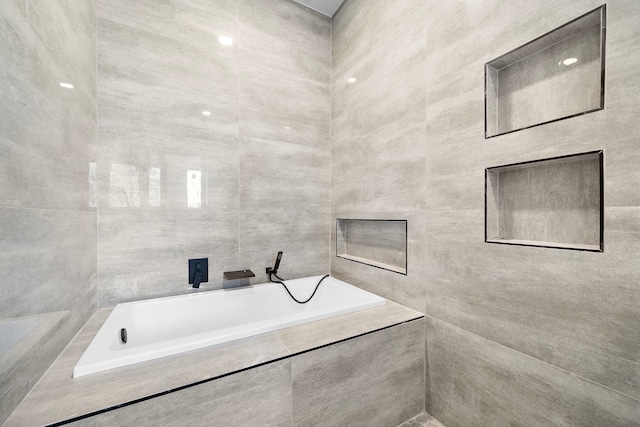 bathroom featuring tile walls and tiled tub