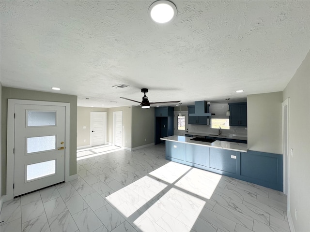 kitchen with decorative backsplash, a textured ceiling, ceiling fan, and sink