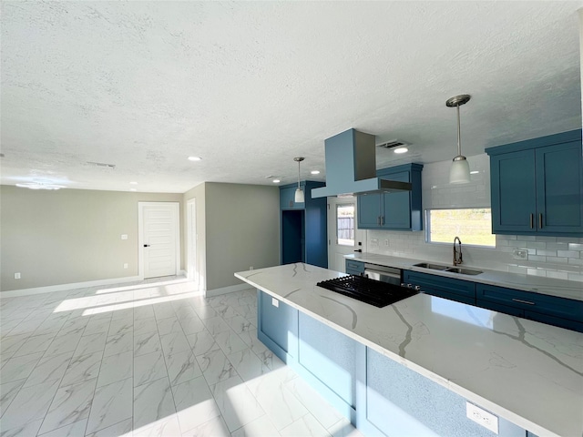 kitchen featuring light stone countertops, hanging light fixtures, blue cabinetry, and sink