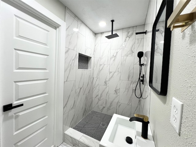 bathroom featuring a tile shower, a textured ceiling, and sink