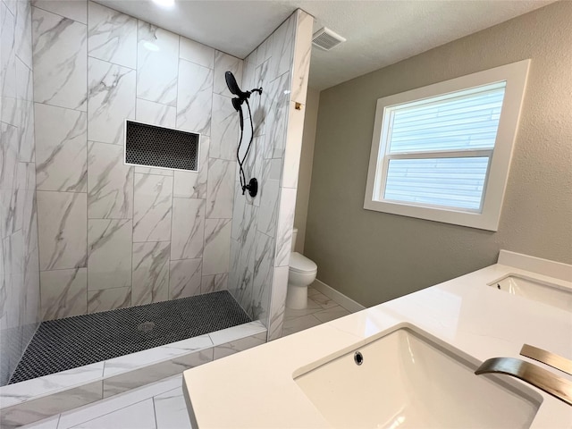 bathroom featuring tiled shower, vanity, and toilet