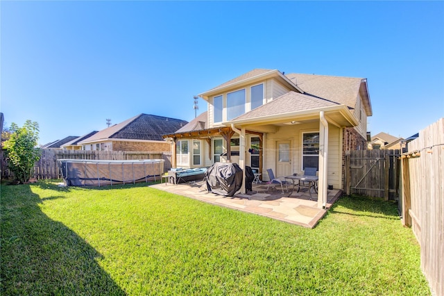 rear view of property with a yard, a covered pool, and a patio area