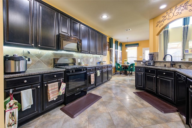 kitchen featuring black appliances, sink, decorative backsplash, dark stone countertops, and decorative light fixtures