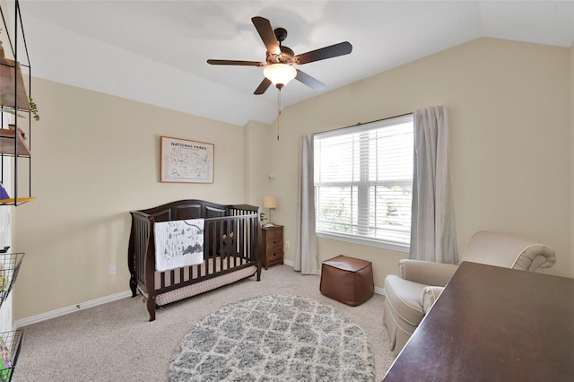 bedroom featuring a crib, vaulted ceiling, light colored carpet, and ceiling fan