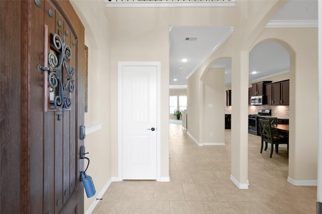 foyer entrance featuring light tile patterned floors and ornamental molding