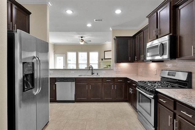 kitchen featuring sink, crown molding, stainless steel appliances, light stone countertops, and backsplash