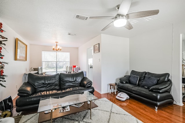 living room featuring hardwood / wood-style floors, ceiling fan with notable chandelier, and a textured ceiling