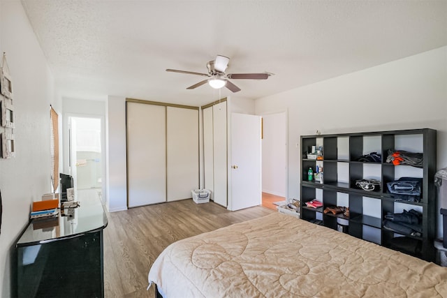 bedroom with ceiling fan, light hardwood / wood-style flooring, and a textured ceiling