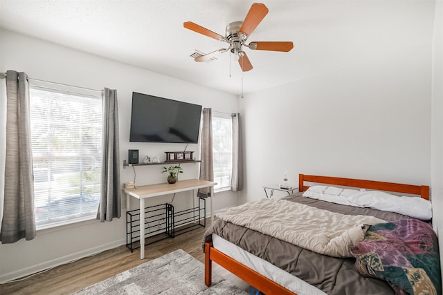 bedroom featuring hardwood / wood-style floors, ceiling fan, and multiple windows