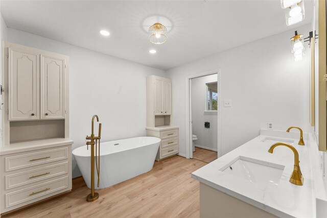 bathroom with vanity, hardwood / wood-style floors, a washtub, and toilet