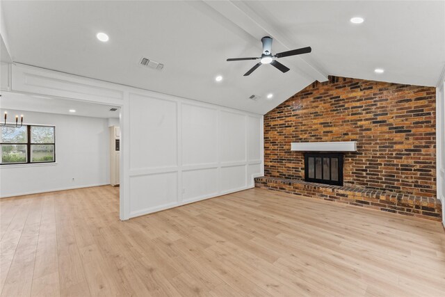 unfurnished living room featuring vaulted ceiling with beams, light hardwood / wood-style floors, ceiling fan with notable chandelier, and a brick fireplace