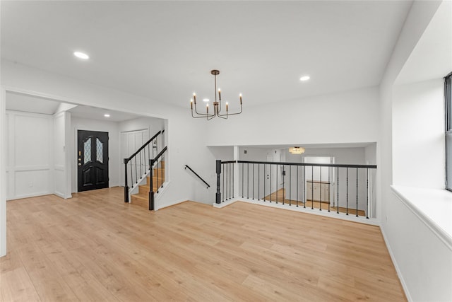 unfurnished room with a notable chandelier and light hardwood / wood-style floors