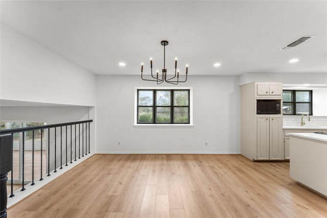 unfurnished dining area with a chandelier, light hardwood / wood-style flooring, and sink