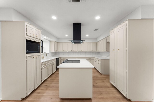 kitchen featuring island exhaust hood, white cabinetry, a kitchen island, and decorative backsplash