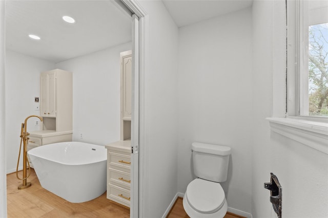 bathroom featuring hardwood / wood-style floors, toilet, and a tub