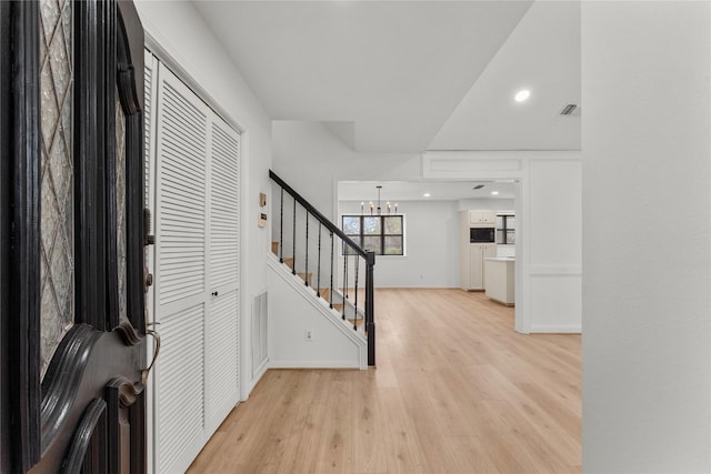 foyer entrance featuring light wood-type flooring and an inviting chandelier