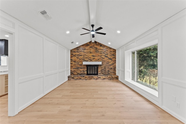 unfurnished living room with lofted ceiling, ceiling fan, light wood-type flooring, a fireplace, and brick wall