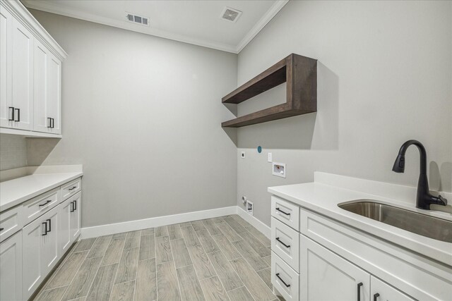 clothes washing area featuring cabinets, crown molding, sink, hookup for a washing machine, and light wood-type flooring