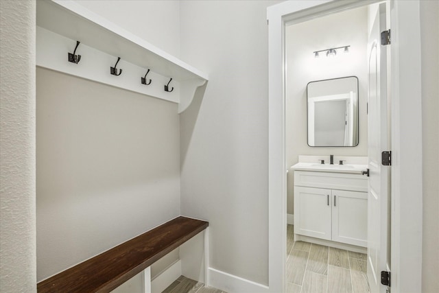 mudroom featuring baseboards and a sink