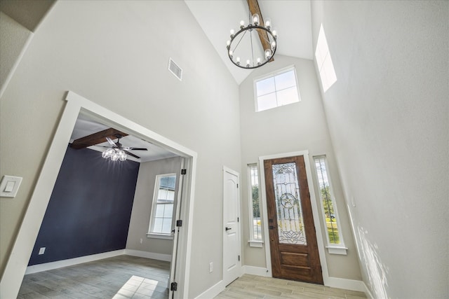 entryway featuring visible vents, high vaulted ceiling, light wood-style flooring, ceiling fan with notable chandelier, and baseboards