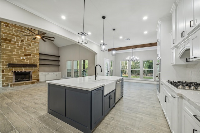 kitchen featuring a sink, wood tiled floor, stainless steel appliances, white cabinetry, and a kitchen island with sink