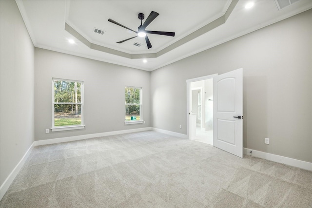 carpeted spare room featuring visible vents, ornamental molding, a ceiling fan, baseboards, and a raised ceiling