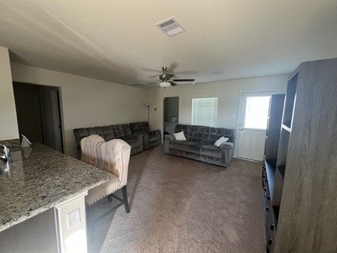 carpeted living room with ceiling fan