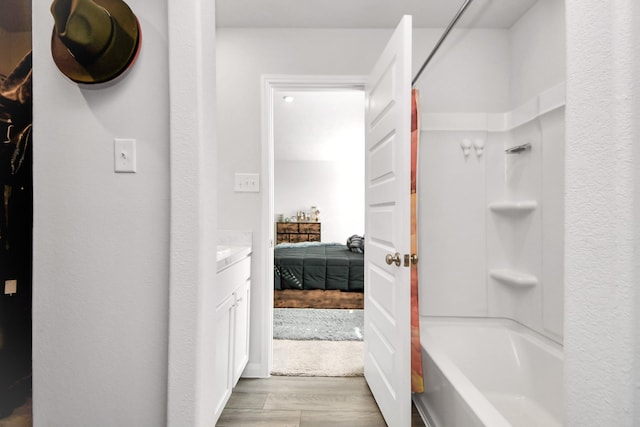 bathroom with wood-type flooring, vanity, and shower / washtub combination